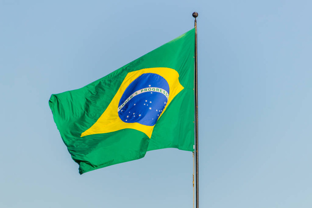 Bandera brasileña ondeando con fondo azul cielo
 - Foto, Imagen