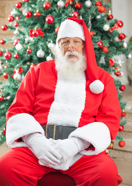 Weihnachtsmann sitzt gegen Weihnachtsbaum - Foto, Bild