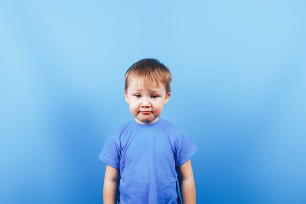 Αναστατωμένο θλιμμένο αγόρι στο μπλε φόντο - Φωτογραφία, εικόνα