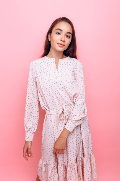 Young woman in a stylish dress. Girl posing on a pink background - Foto, immagini