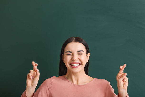 Female student with crossed fingers near blackboard in classroom - Foto, Imagen