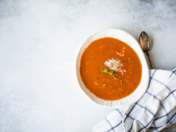 Fresh Tomato soup with cheese and fresh pea sprout in white rustic bowl on grey background. Copy space. top view - Zdjęcie, obraz