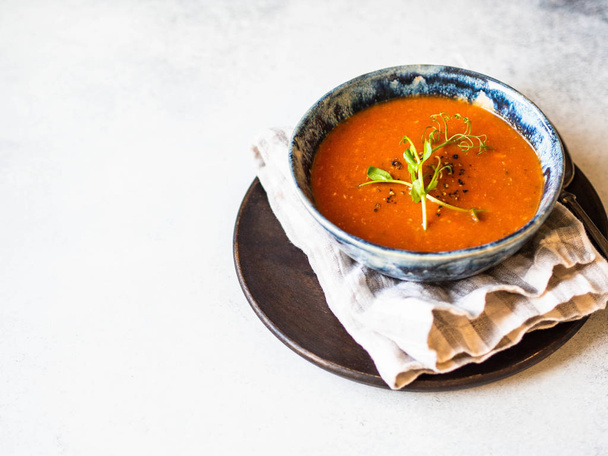 Fresh Tomato soup with spices and fresh pea sprouts in blue rustic bowl on light background. - 写真・画像