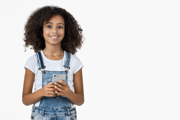 Little smiling teenage girl using mobile phone isolated on white background - Фото, зображення