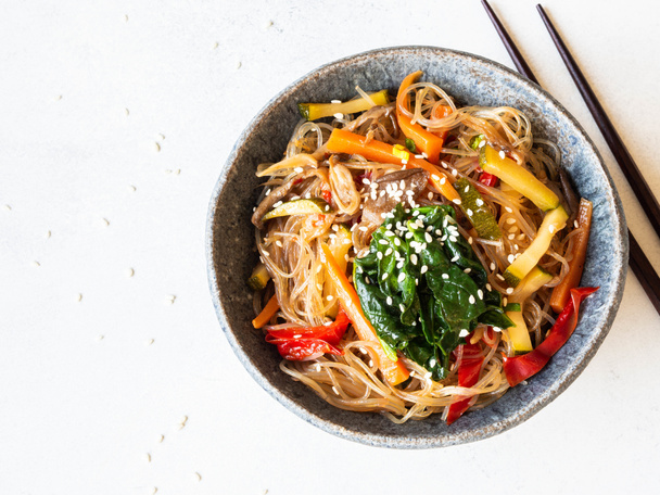 Blue bowl with rice noodles and various vegetables steer fry on a grey background. - Φωτογραφία, εικόνα