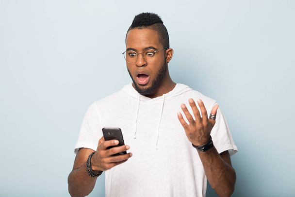 Surprised african American man get unexpected message on cellphone - Φωτογραφία, εικόνα