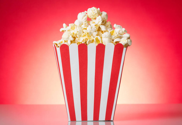 Container with popcorn isolated on a red. - Foto, imagen