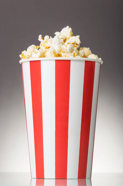 Container with popcorn isolated on a gray. - Foto, imagen