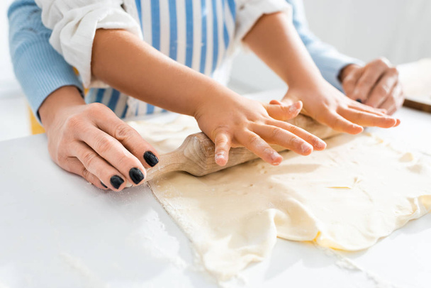 cropped view of mother and daughter rolling dough on table  - Valokuva, kuva
