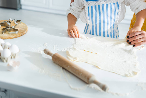 cropped view of mother and daughter cooking and holding dough  - Foto, Imagen