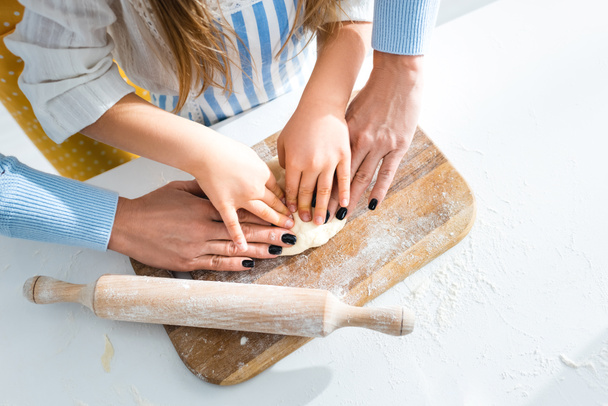 cropped view of mother and daughter cooking with dough on cutting board  - Fotoğraf, Görsel