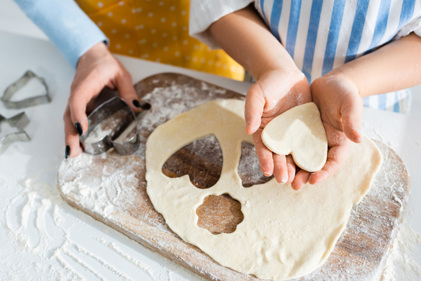 cropped view of mother holding dough mold and daughter holding heart-shaped dough  - Foto, Imagem