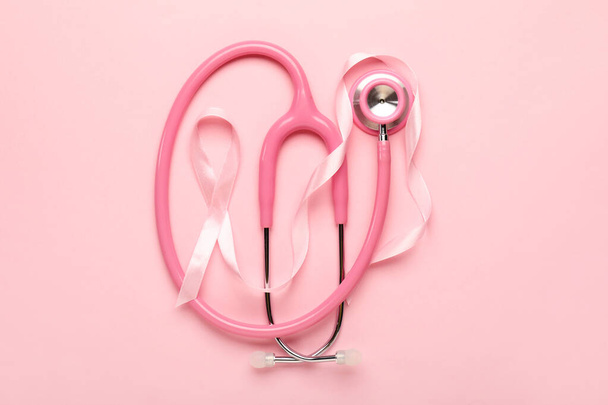 Розовая лента со стетоскопом на цветном фоне. Концепция информированности о раке груди
 - Фото, изображение