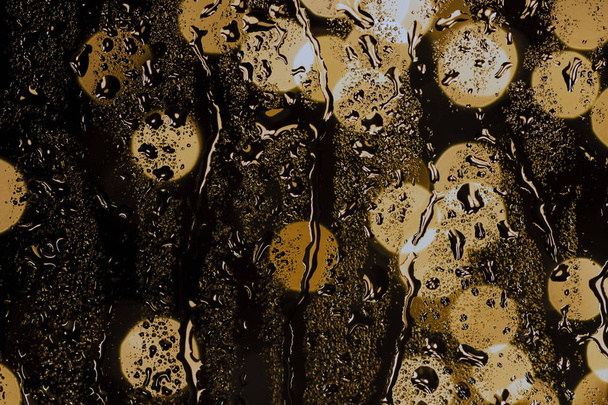 rain drops on night window and golden bokeh lights, drops background on night time  - Valokuva, kuva