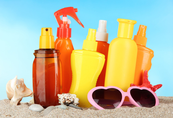 Bottles with suntan cream and sunglasses, on blue background - Fotó, kép