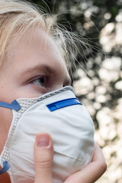 Ξανθό κορίτσι φορώντας P2 N95 αναπνευστική μάσκα προστασίας για να μειώσει την ποσότητα των σωματιδίων Pm2.5 αναπνοής - Φωτογραφία, εικόνα
