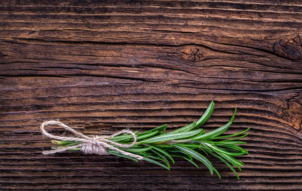 Fresh fragrant rosemary branch on vintage wooden table - Foto, afbeelding