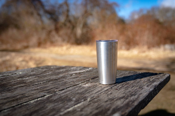 Coffee mug left behind on a picnic table - Foto, imagen