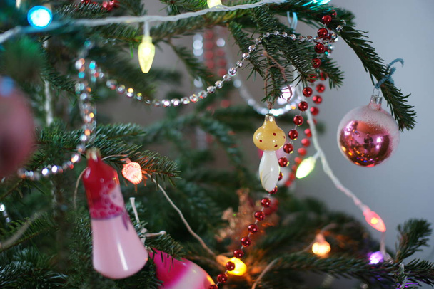 colored toys and garlands and ribbons on green fir tree in room background - Foto, immagini