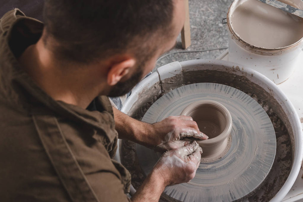 Potier faisant une cruche d'argile blanche sur le cercle de roue du potier en atelier, concept de créativité et d'art, photo horizontale, vue du dessus
 - Photo, image