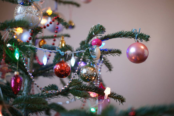 green fir tree with colored toys and garlands in room background - Fotó, kép