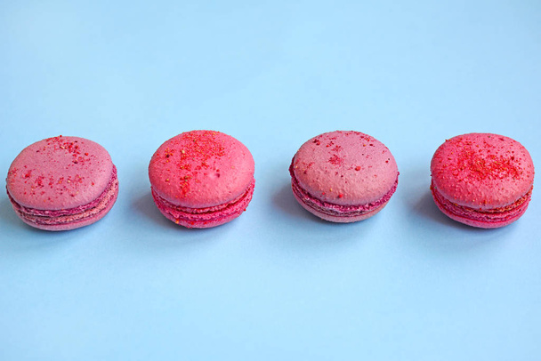 Four pink macaroons on a light blue background, top view - Foto, afbeelding
