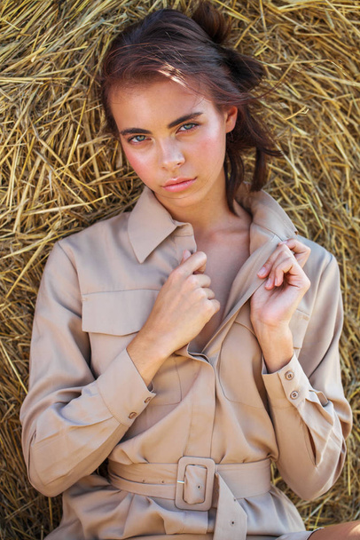 Beautiful girl in a beige dress posing on a background of haysta - Foto, Imagem