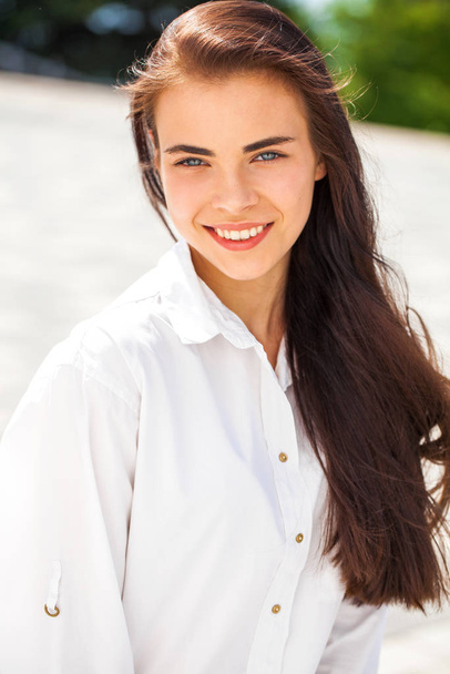 Young beautiful brunette girl in white shirt posing on spring pa - Фото, изображение