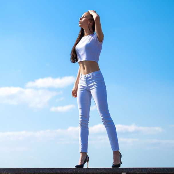 Beautiful brunette woman posing against blue sky bright sunny we - Фото, зображення