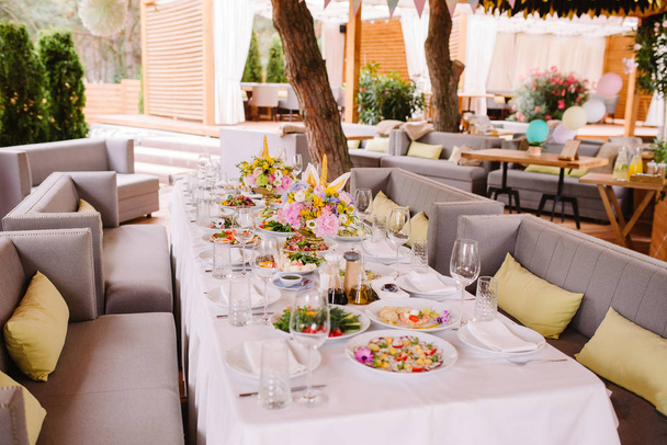 Festliches Essen auf dem Tisch im Restaurant. Stilvolle Tischdekoration mit Blumen in einer Vase und einer Kerze. - Foto, Bild