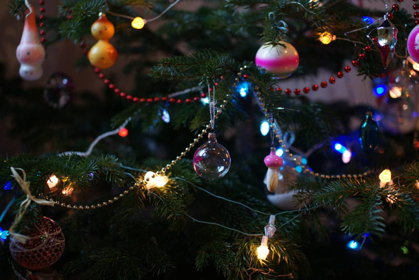green fir tree with colored toys and garlands in room background - Foto, afbeelding