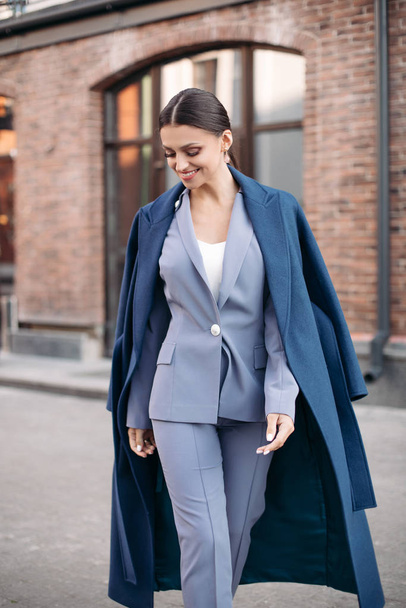 Attractive cheerful brunette in suit and coat. - Фото, изображение