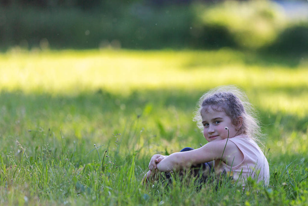 kaunis kihara tyttö istuu nurmikolla
 - Valokuva, kuva