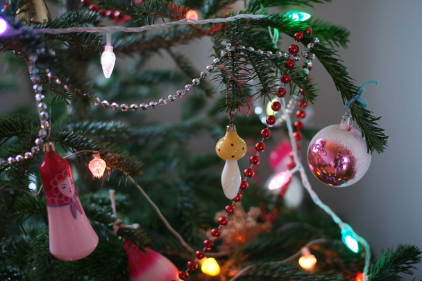 colored toys and garlands and ribbons on green fir tree in room background - Fotografie, Obrázek