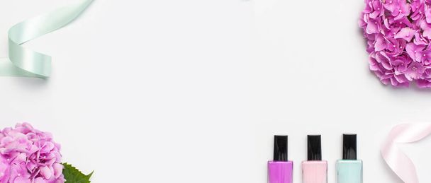 Decoratieve cosmetica, nagellak. Set van verschillende vernissen voor manicure nagels op lichte achtergrond met bloemen van roze Hydrangea Top View platte lay mock up. Vrouwelijke cosmetica. Beauty blogger concept - Foto, afbeelding