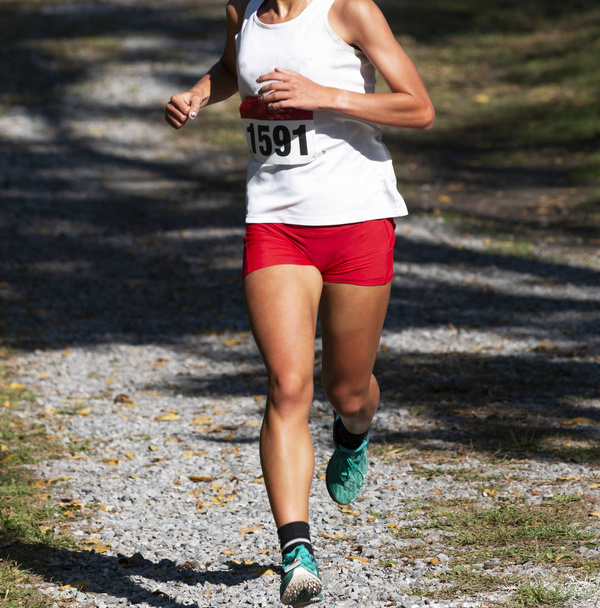 Chica de secundaria corriendo carrera de 5K sobre rocas cubiertas por la sombra de tr
 - Foto, Imagen