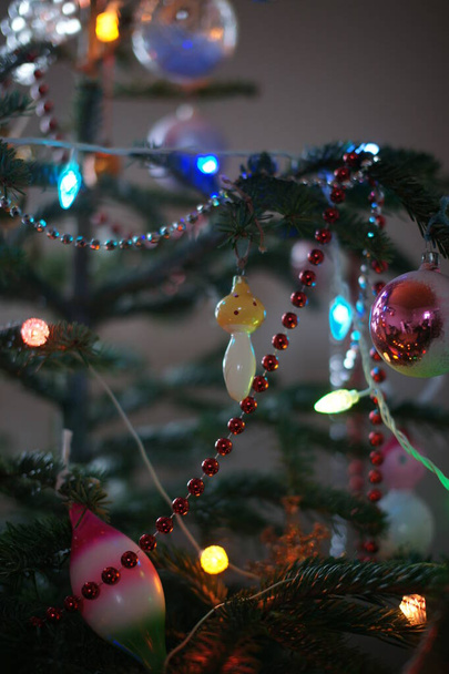 green fir tree with colored toys and garlands in room background - Foto, imagen