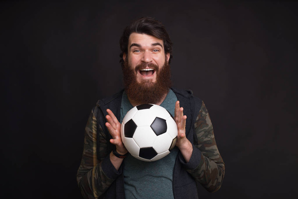 I caught the ball. Young bearded hipster is holding a soccer or football ball. - Foto, Imagem