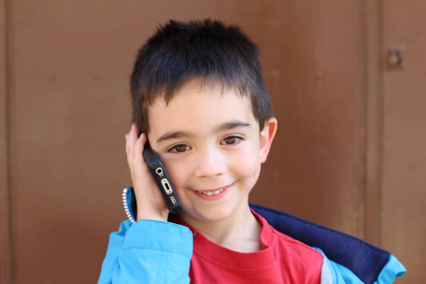 Outdoor portret słodkie dziecko chłopiec rozmowy przez telefon na zewnątrz - Zdjęcie, obraz