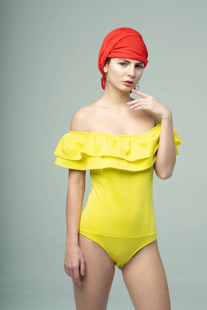 young beautiful girl pose in the studio in a yellow bathing suit - Zdjęcie, obraz