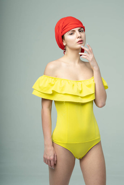 junge schöne Mädchen posieren im Studio in einem gelben Badeanzug - Foto, Bild