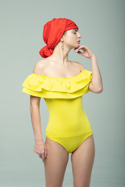 young beautiful girl pose in the studio in a yellow bathing suit - Φωτογραφία, εικόνα