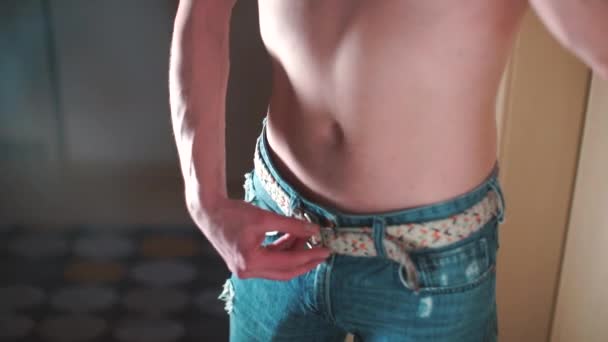 Egy férfi ing nélkül leveszi a nadrágját.  - Felvétel, videó