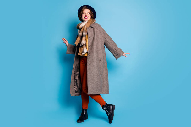 Full length photo of pretty traveler lady walk street good mood day lucky trip abroad wear casual long grey coat scarf trousers cap footwear isolated blue color background - Fotografie, Obrázek
