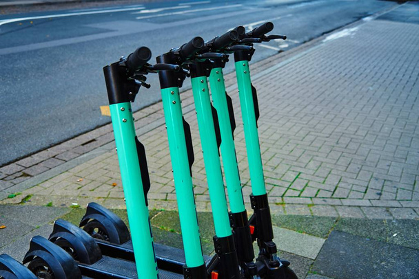 A closeup shot of green and black scooters standing in the street - 写真・画像