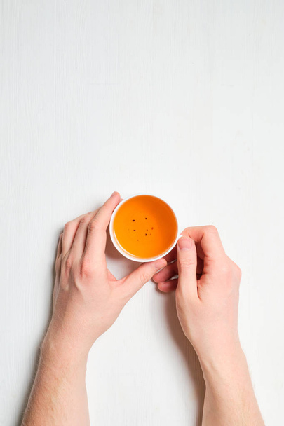 Las manos sostienen una taza de té fresco sobre un fondo de madera blanca
. - Foto, imagen