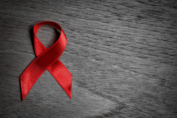 rotes Band hilft Bewusstsein für den Welt-Hiv / Aids-Tag auf schwarzem und weißem Holzhintergrund. - Foto, Bild