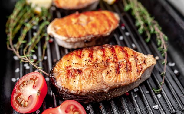 Grilled salmon steaks with on a grill pan with spices on a stone background with copy space for your background - Fotoğraf, Görsel