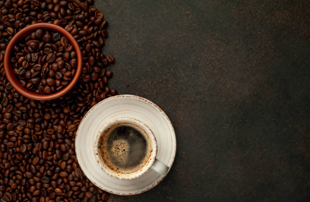 Bovenaanzicht van kopje smakelijke koffie en bonen op een stenen achtergrond met ruimte voor tekst  - Foto, afbeelding