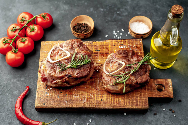 grilled steaks, with tomatoes and spices on a stone background  - Photo, Image